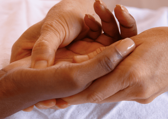 Massage therapist performing hand reflexology on a client